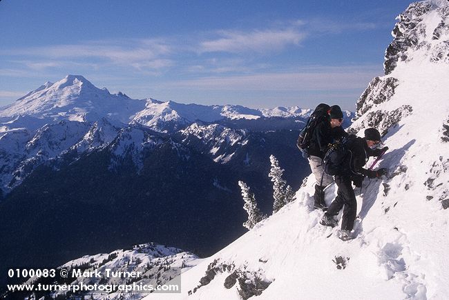 0100083 Zack Nowak, Mimi Allin traverse steep snow-covered ridge to Goat Mtn. east summit. Mt. Baker Wilderness Goat Mtn., WA. © Mark Turner