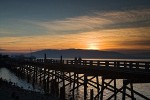 0700134 Sunset over South Bay Trail trestle over edge of Bellingham Bay w/ silhouettes of people walking, Lummi Island bkgnd. Bellingham, Boulevard Park, WA. © Mark Turner