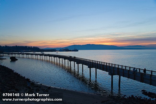 0700148 Taylor Dock over Bellingham Bay w/ walkers, Fairhaven shipyards & Lummi Island bkgnd at sunset. Bellingham, Boulevard Park, WA. © Mark Turner