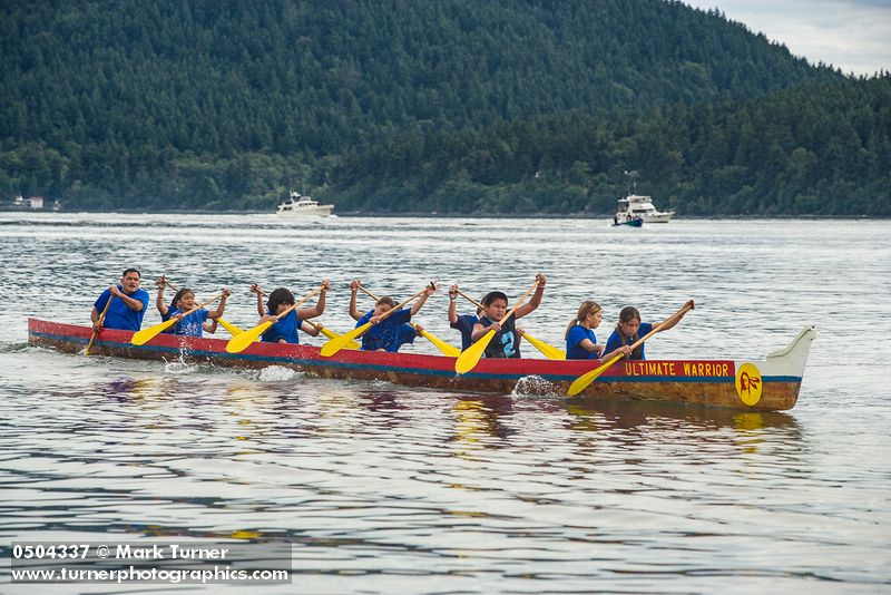 0504337 Boys & girls (junior buckskins 13 & under) paddle 11-man canoe to finish, Lummi Stommish canoe races. Lummi Nation, WA. © Mark Turner