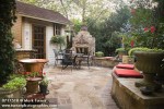 0717518 Flagstone patio w/ stone fireplace, outdoor dining set, red cushions on curving low stone wall, garden shed [Taxus sp.; Hibiscus cv.]. Stenseth, Oklahoma City, OK. © Mark Turner