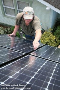 0803067 Tim Nelson bolts solar panel into array. Turner, Bellingham, WA. © Mark Turner